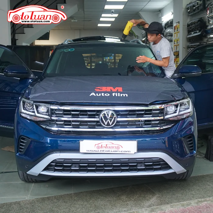 Kỹ thuật viên dùng máy khò xử lý phim trên kính lái Volkswagen Teramont tại Ô tô Tuấn.